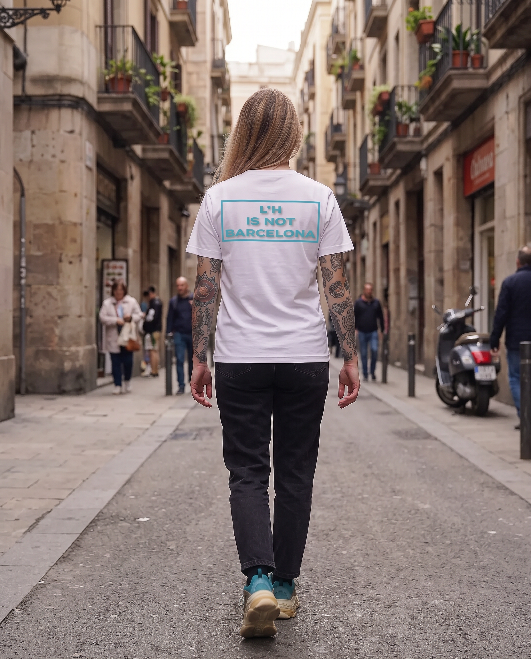Chica rubia de espaldas por la calle con la camiseta L'H IS NOT BARCELONA