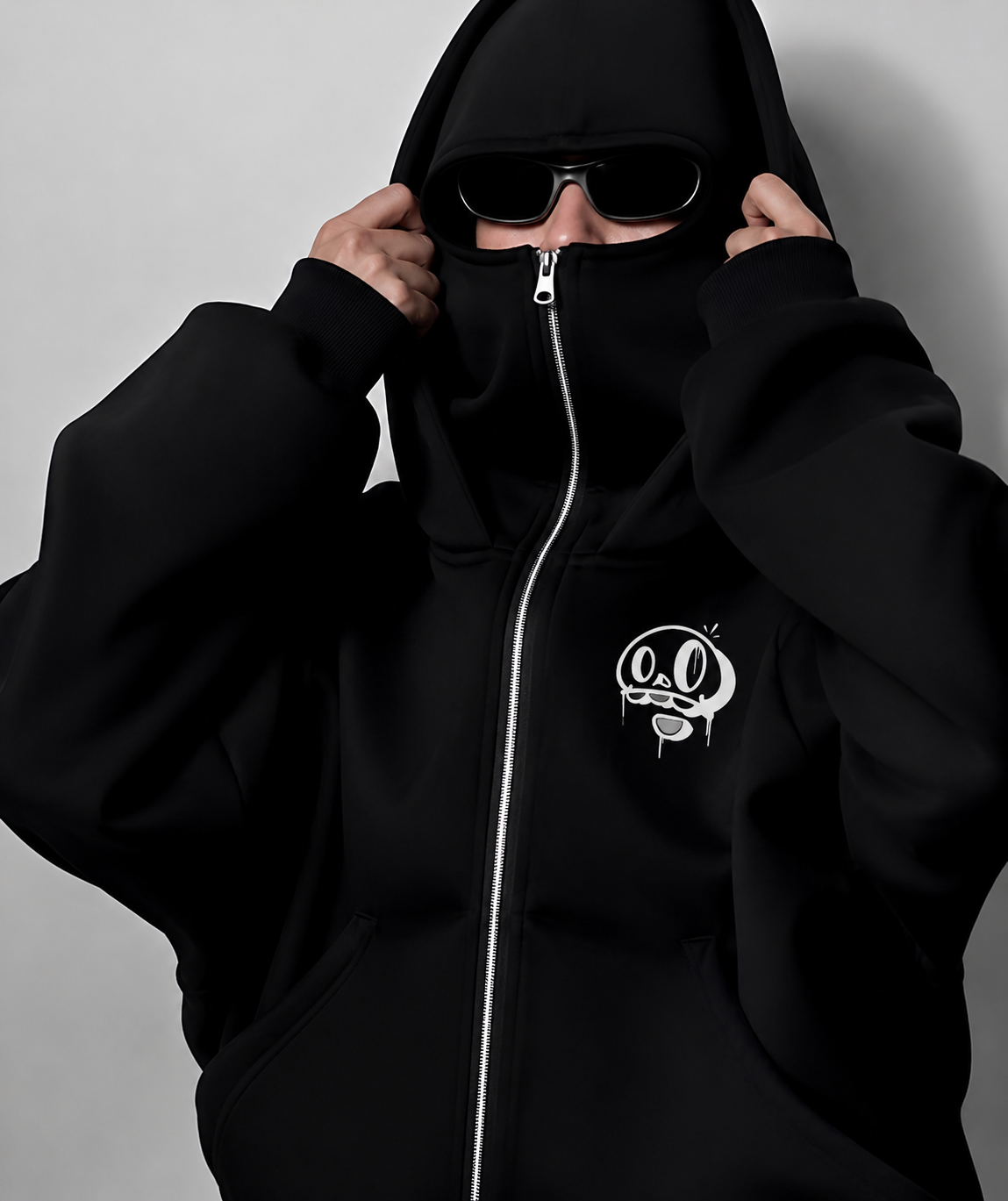 Chico con capucha y gafas con la sudadera negra Wake Up con la mascota bordada en el pecho